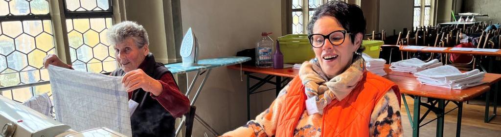 Im Hintergrund (auf der Empore) wird fleißig gebügelt