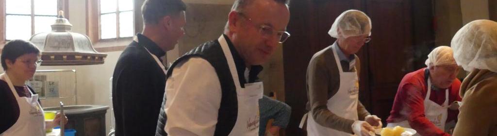 Landesbischof Dr. Christian Kopp mit Vesperkirche-Schürze an der Essensausgabe